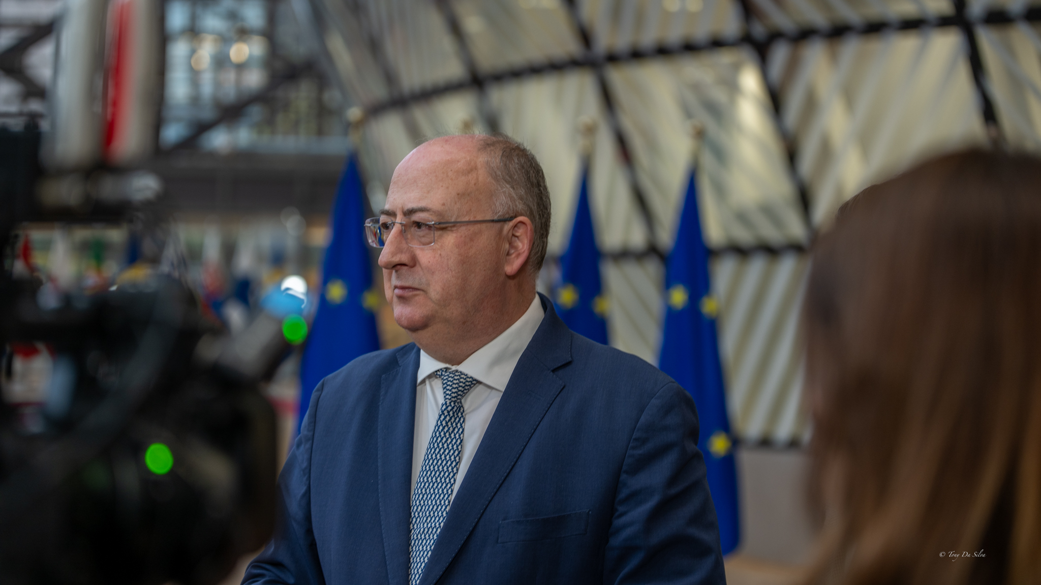 Ministro português faz declaração à comunicação social em Bruxelas, com bandeiras da União Europeia ao fundo, após negociações sobre quotas de pesca.