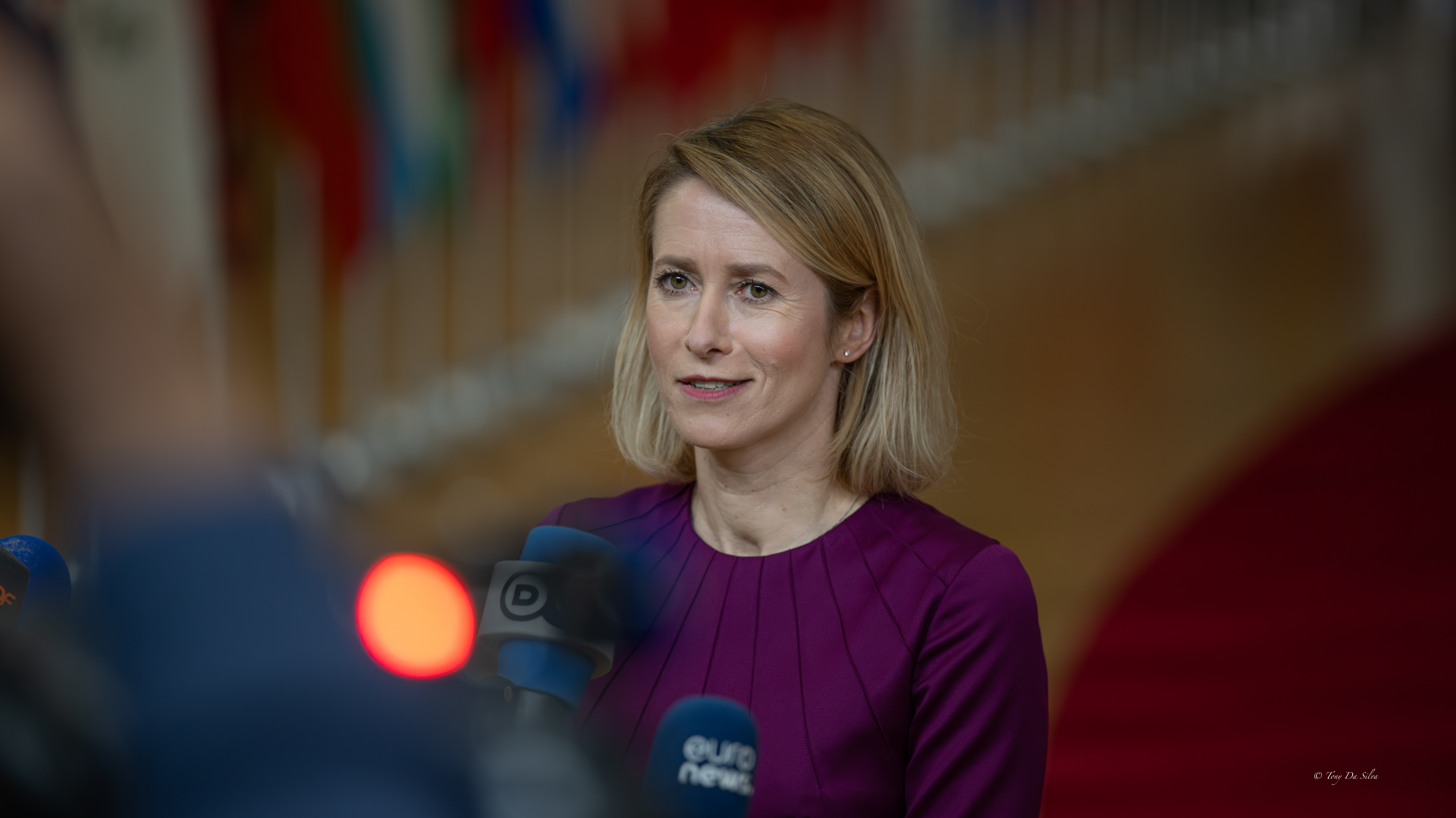 Kaja Kallas, Alta Representante da UE para os Negócios Estrangeiros, fala numa conferência de imprensa em Bruxelas, com microfones à sua frente e bandeiras de vários países ao fundo.