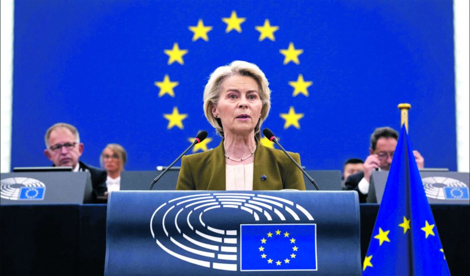 A presidente da Comissão Europeia discursa no Parlamento Europeu, com a bandeira da União Europeia ao fundo.