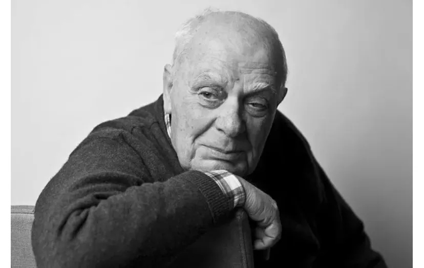 Retrato a preto e branco de um homem idoso, com expressão pensativa, sentado e apoiado num braço, em fundo neutro.