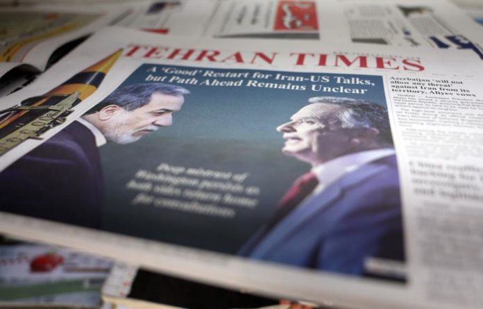 Capa do jornal Tehran Times com a fotografia de dois homens frente a frente, representando o Irão e os Estados Unidos, e o título sobre negociações entre ambos os países.