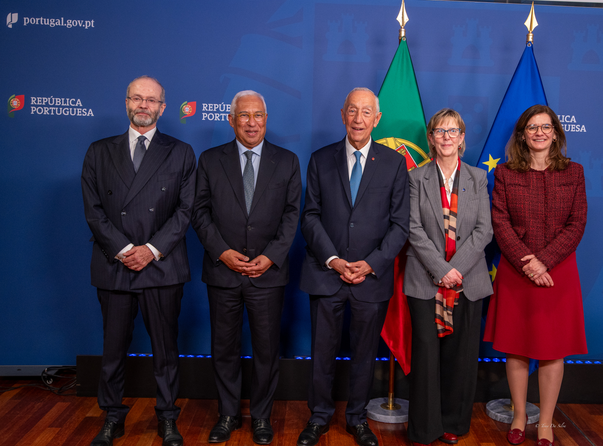 Cinco pessoas em traje formal posam para fotografia oficial em frente às bandeiras de Portugal e da União Europeia, num ambiente institucional.