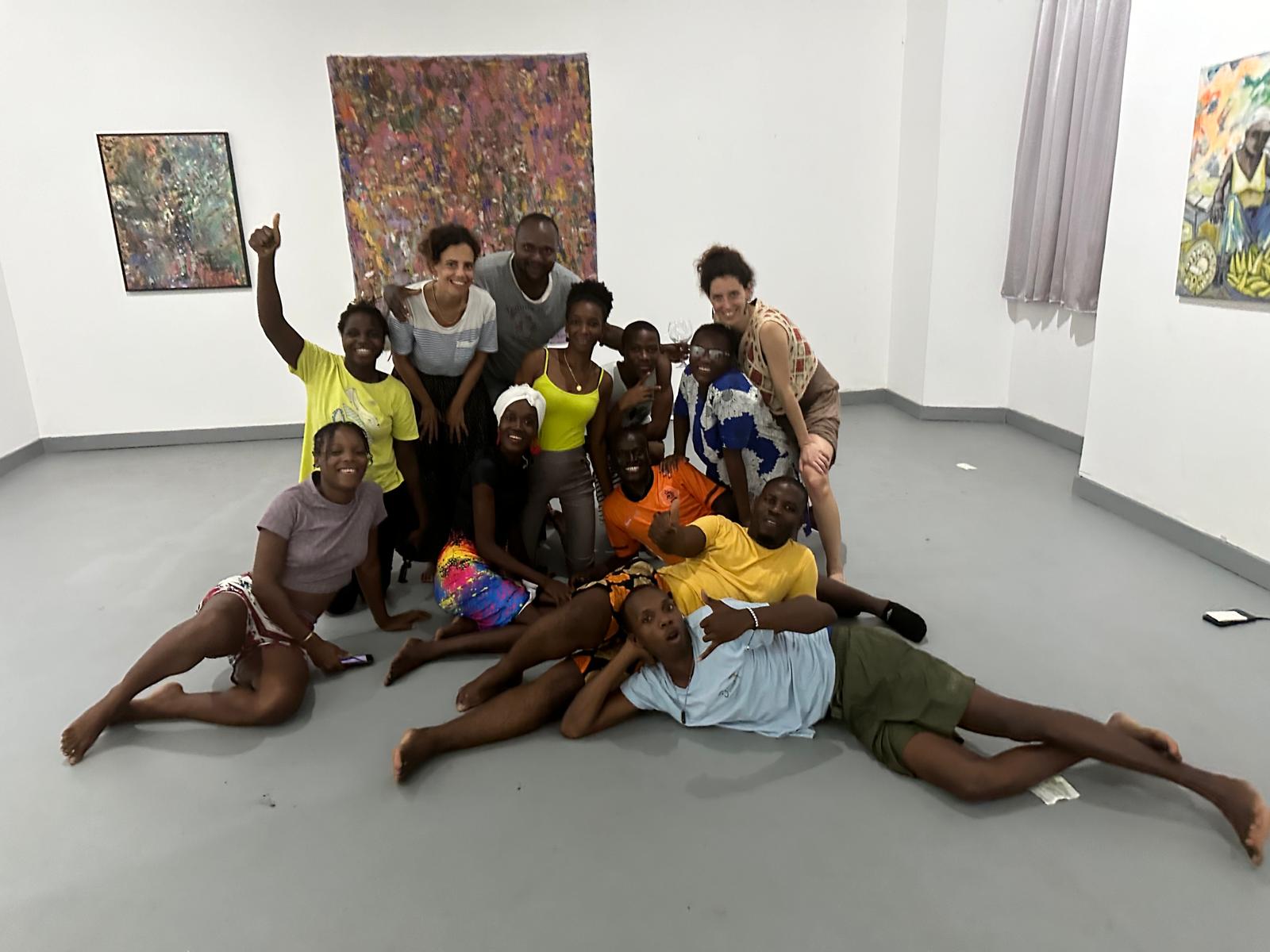 Grupo de crianças e adultos, de diferentes idades, reunidos de forma descontraída numa galeria de arte, refletindo ambiente de inclusão, participação comunitária e ligação entre arte e intervenção social, em linha com o papel do teatro em São Tomé e Príncipe descrito no artigo.